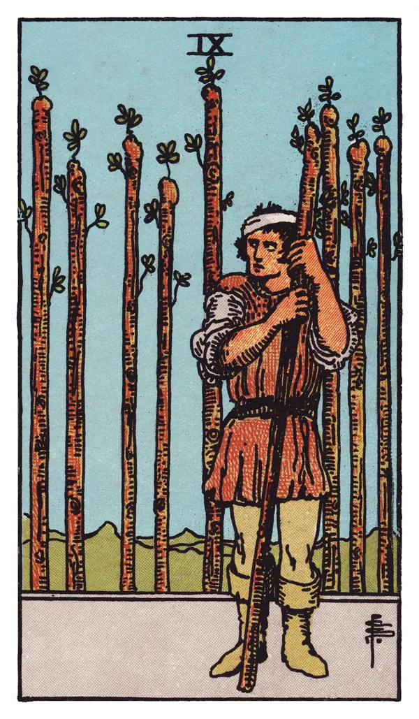 The Nine of Wands from the Rider-Waite-Smith deck: a bandaged man leans warily on a single upright wand, glancing back over his shoulder, while eight other wands stand planted behind him in a fence-like row, his stance guarded and his posture tired but unbroken.