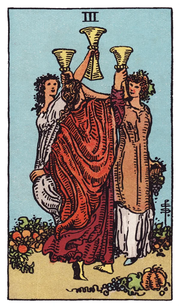 The Three of Cups from the Rider-Waite-Smith deck: three women dance in a circle in a garden, each raising a cup high in a toast, wearing crowns of flowers and fruit; gourds, grapes, and pumpkins lie scattered at their feet.