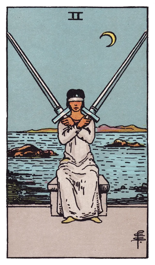 The Two of Swords from the Rider-Waite-Smith deck: a woman in pale robes sits blindfolded at the edge of a rocky shoreline, two full-length swords crossed and balanced against her shoulders, her arms folded over her chest to hold them steady, a choppy sea and jagged rocks behind her under a low crescent moon.